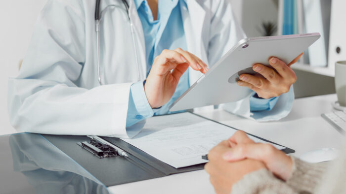 Close up of Young Asian woman doctors medical results during consultation on tablet computer with female patient sick with cancer in health clinic. Medical health care.